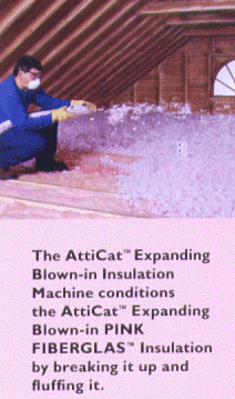 A man in blue overall uniform insulating an attic